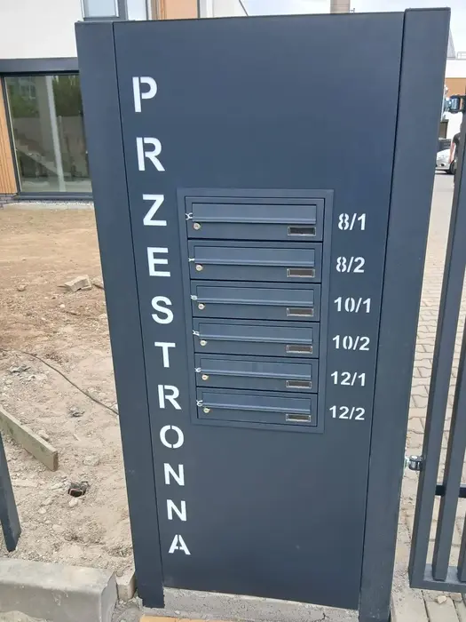 Briefkastenanlage mit Hausnummer in einem Metallzaun