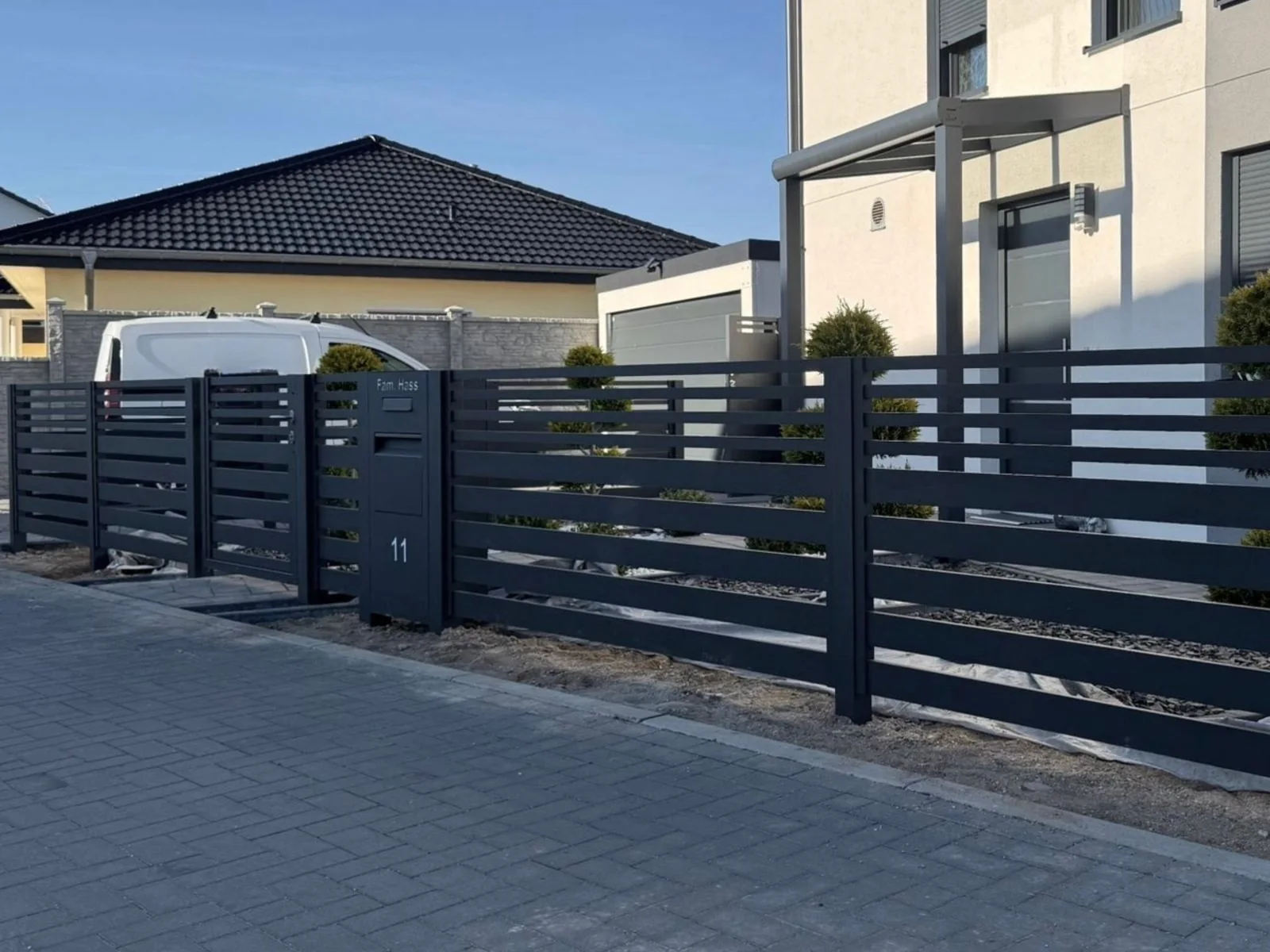 Zaunanlage mit horizontalen Profilen vor einem Wohnhaus