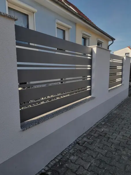 Moderner Aluminiumzaun mit horizontalen Profilen zwischen gemauerten Pfeilern
