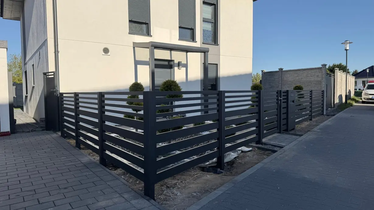 Moderne Zaunanlage mit horizontalen Profilen vor einem Wohnhaus